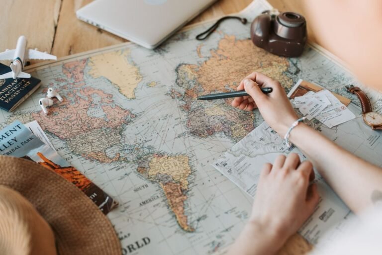 Hands marking a route on a world map
